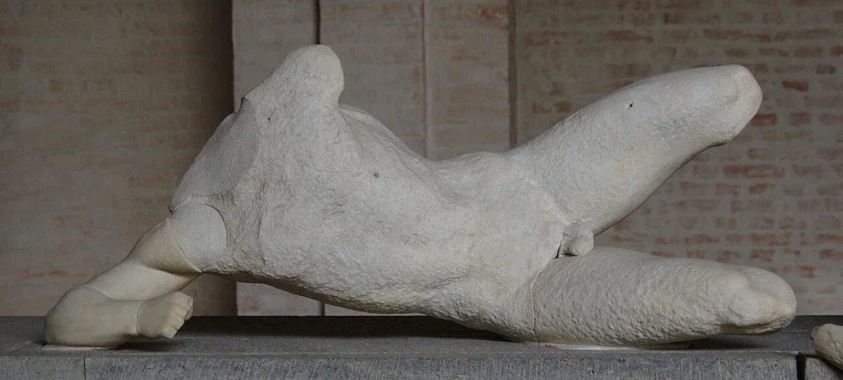 Marble figure of a naked warrior lying fallen on his side, from a temple pediment.