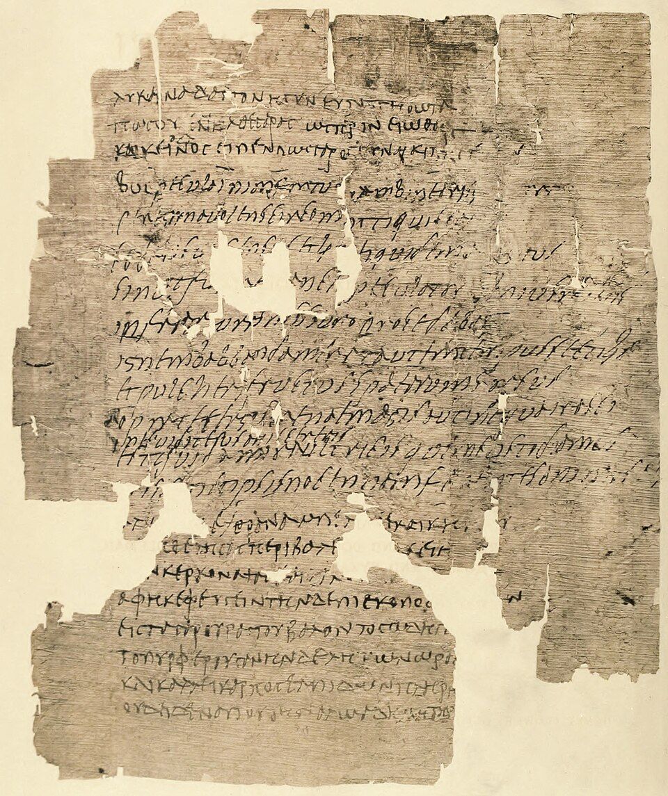 A damaged papyrus sheet with lines of Greek and Latin in a cursive hand.