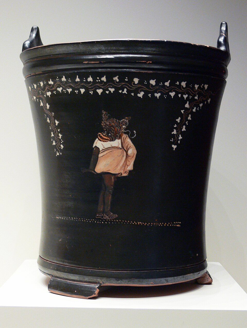 Black bucket-shaped vase painted with a small figure of a costumed comic actor.