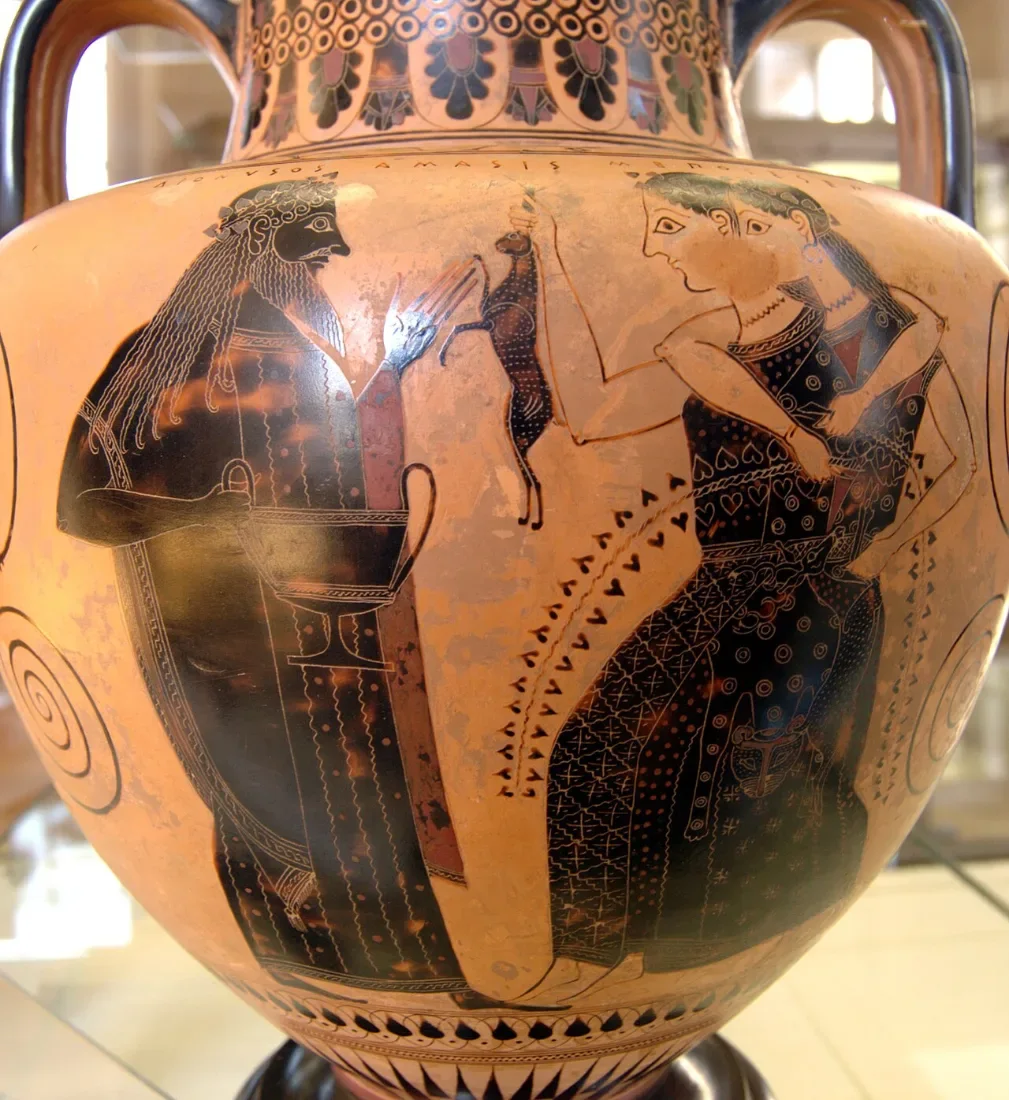 A black-figure amphora: a bearded god with a cup faces two women dancing arm in arm.