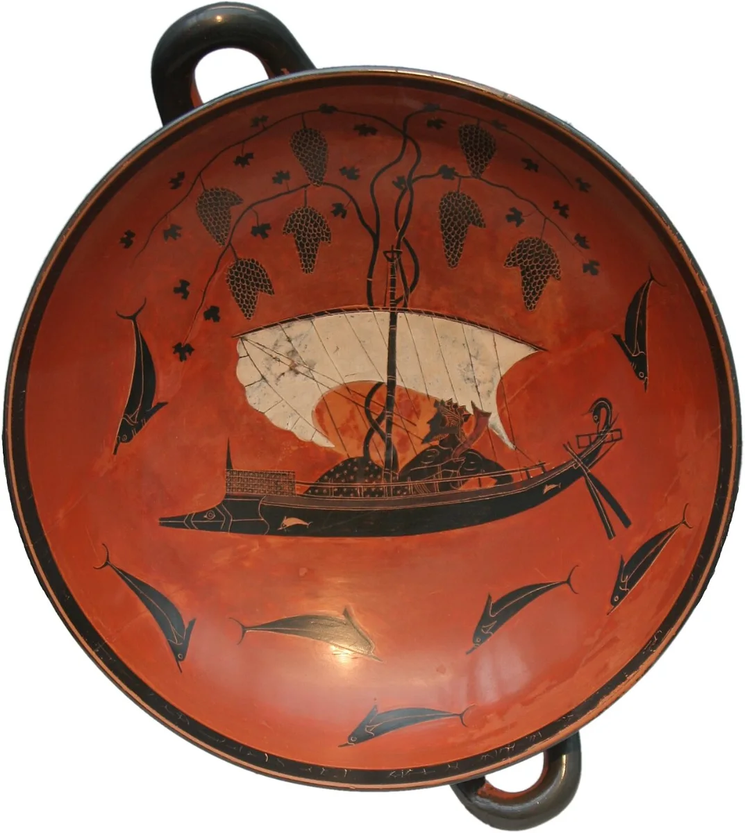 Interior of a black-figure cup: Dionysus reclines in a ship whose mast sprouts vines, dolphins leaping round it.