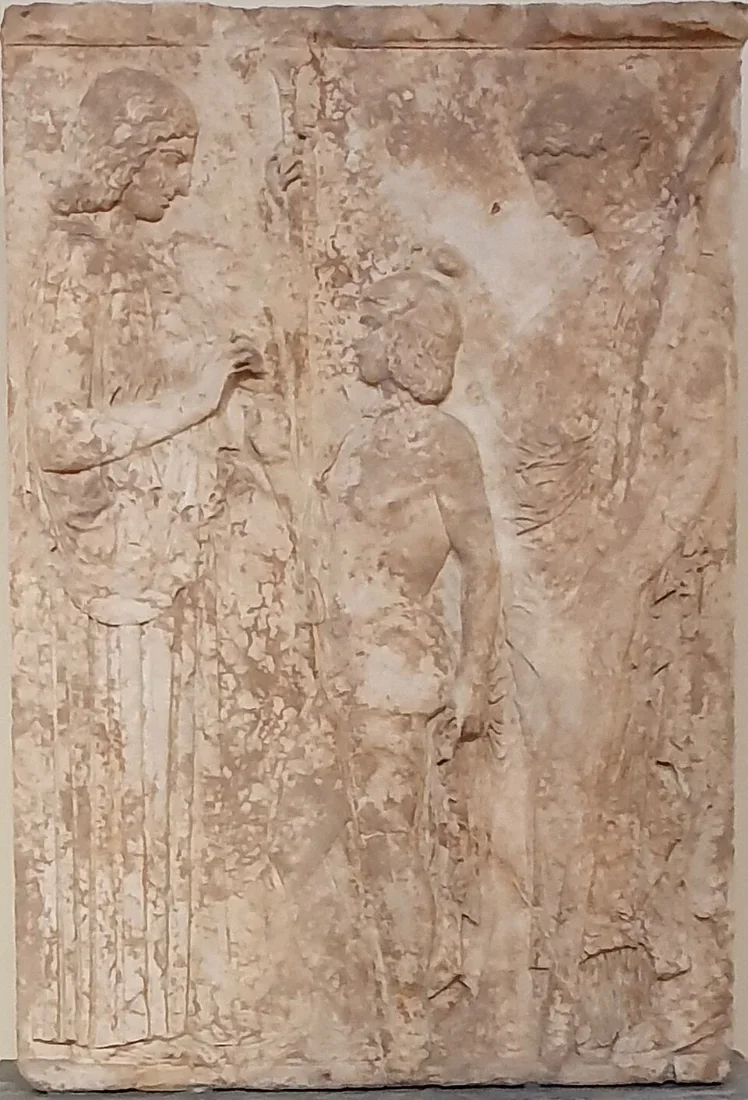 A tall marble relief: two women facing each other with a boy between them.