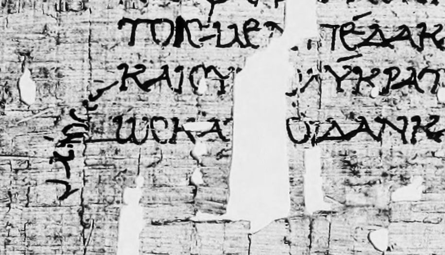 Photograph of papyrus fragments with Greek text and a curved sign in the margin.