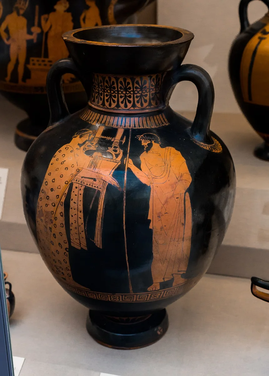 Red-figure amphora: a young kithara-player in a long embroidered robe stands before a bearded man holding a staff.