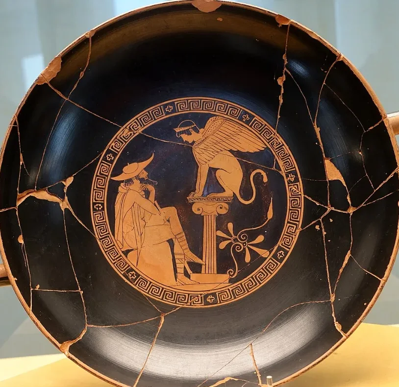 A cup with a painting inside: a traveller seated before a sphinx on a column.