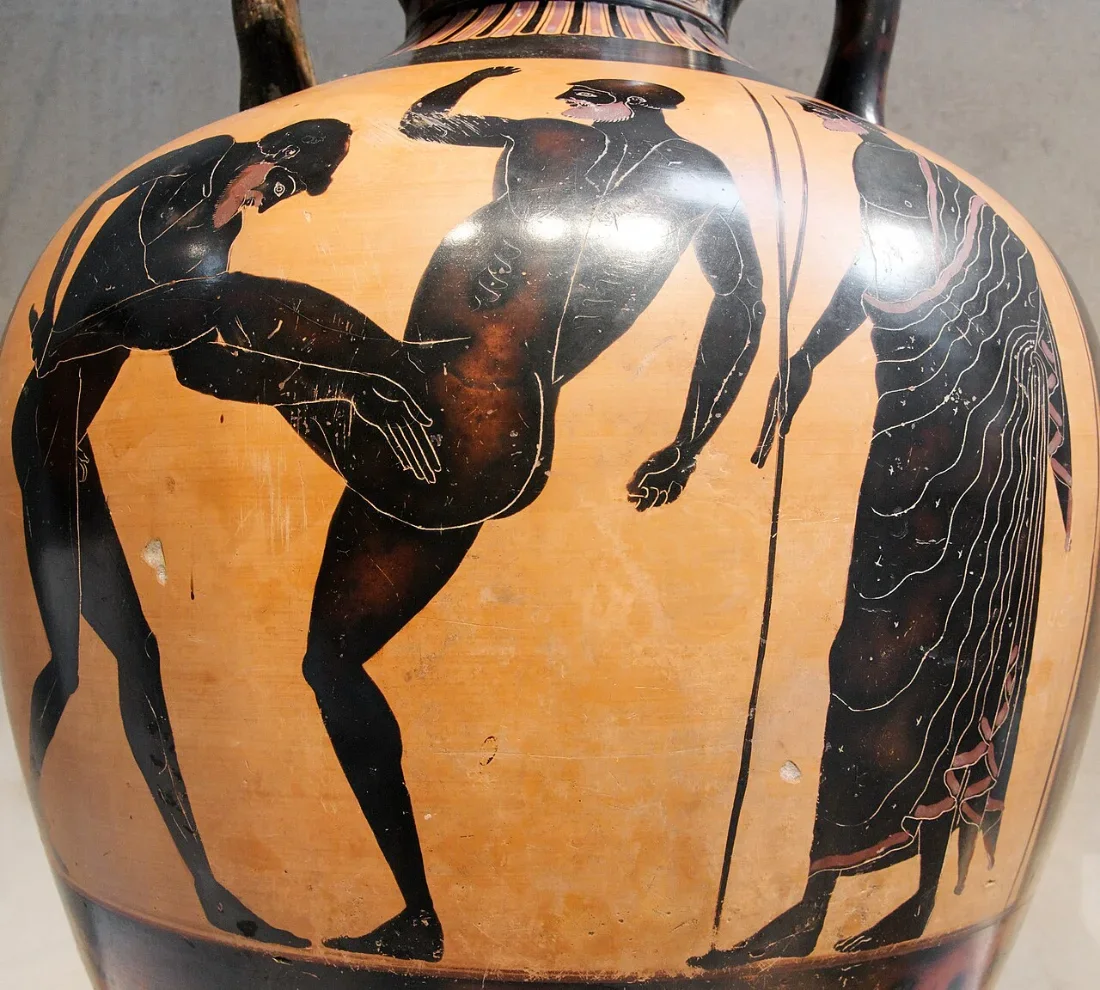 A black-figure amphora: two naked fighters locked together, a judge with a rod beside them.