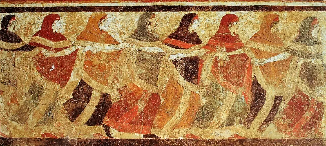 A painted frieze of women in coloured cloaks dancing hand in hand.