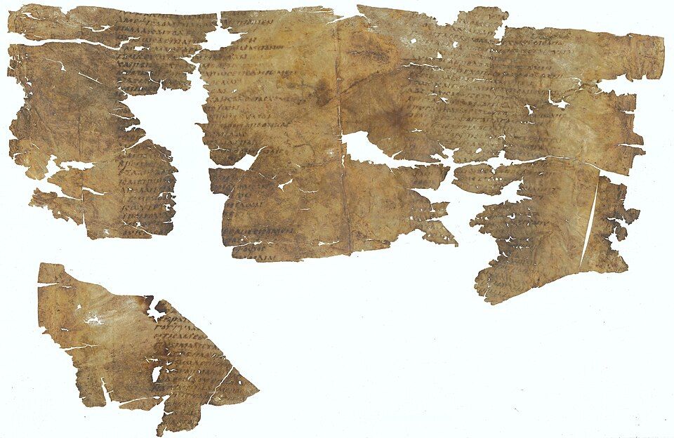 Several torn pieces of parchment with faded lines of Greek text, laid out side by side.