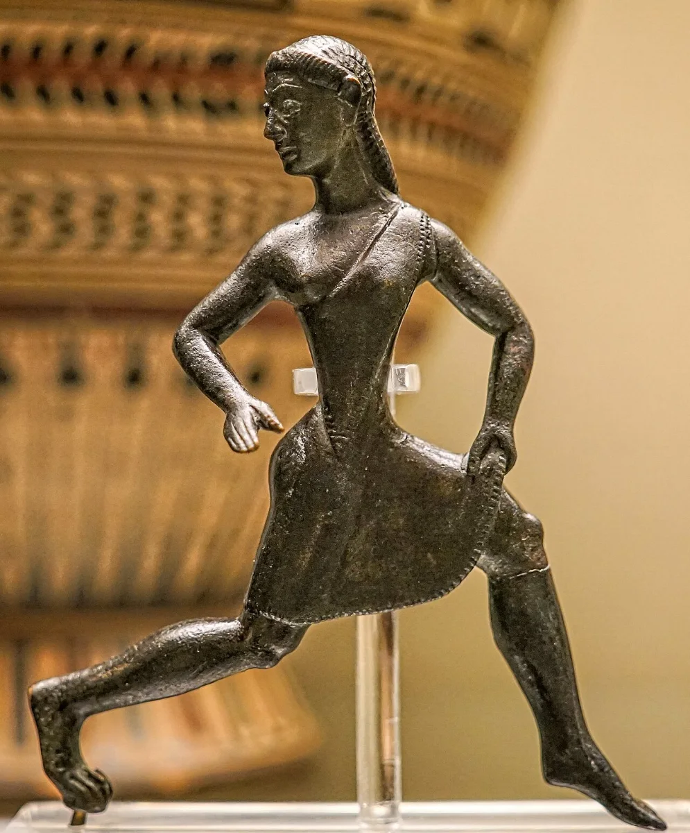 Bronze statuette of a girl in a short tunic, running, one hand lifting her skirt.