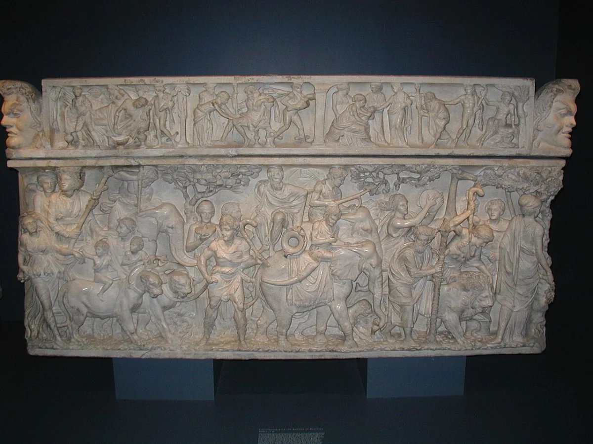 A marble sarcophagus carved all round with a crowded procession of figures, elephants and panthers.